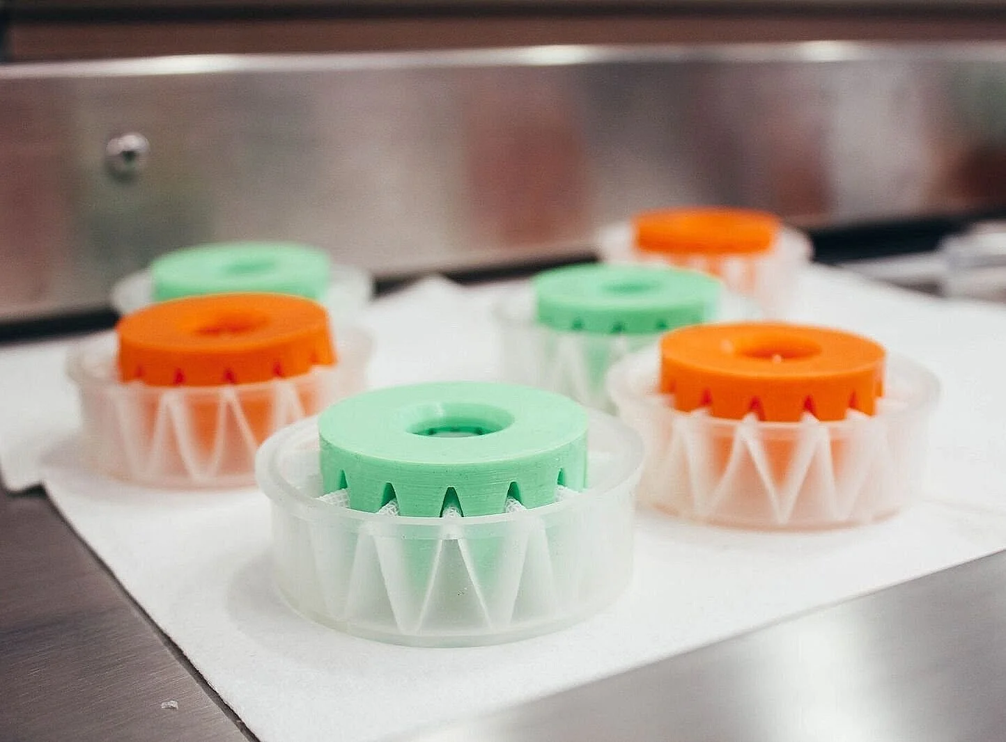 Orange and green Hemafuse filter components arranged on a clean manufacturing surface.